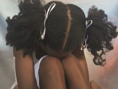 A sad little girl sitting on the floor