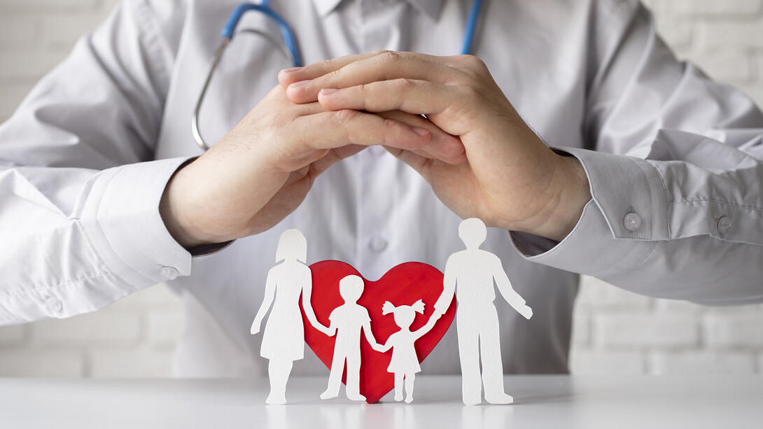 Physician with stethoscope and protective hands shielding a cardboard family: symbolizing healthcare collaboration and patient-centered care