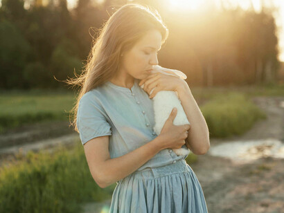 A girl dressed in ligh blue hold a white rabbit, reminiscent of Alice in Wonderland
