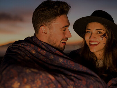 Romance as a young couple sits wrapped in a blanket by the sea, embodying the essence of love and togetherness in their relationship