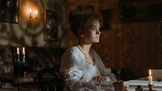 A noblewoman writing by candlelight in an elegant historic interior