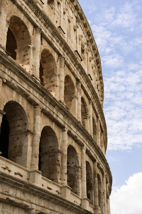 Looking through the arches of the Colosseum in Rome, Italy, one can almost hear the distant echoes of roaring crowds and feel the weight of history that permeates this iconic structure