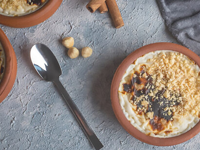 Sütlaç, a beloved Turkish dessert, showcases the perfect blend of creamy rice pudding and earthy hazelnuts, served in a rustic earthenware casserol