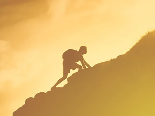 A determined man ascends a mountain cliff, diligently striving to achieve his goals through hard work and perseverance