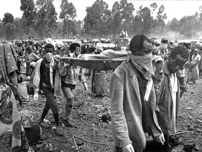 Julio de 1994, hombres enmascarados se llevan a una víctima del cólera en el campo de refugiados de Goma en Zaire. Escribiendo para The Globe and Mail el 30 de julio de 1994, el fotógrafo Russell Monk describió los peligros mortales de las enfermedades, el hambre y el hacinamiento que enfrentaban los refugiados en el campo