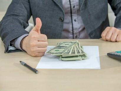 In his office, a young businessman counts cash, reflecting the drive for corporate greed