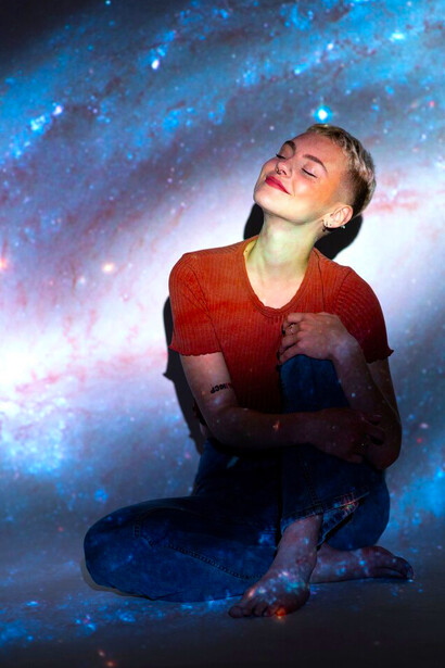 A portrait of a young woman with the universe projected around her, emanating spiritual energy, a vibrant energy field, and balanced chakra energy