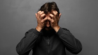 A man holding his head visibly stressed and panicked, representing the power of fear and the influence it has on people