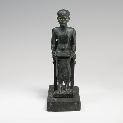 Questa statuetta raffigura Imhotep, l'architetto geniale e scriba reale sotto il faraone Djoser. È celebrato come l'ideatore della Piramide a gradoni di Saqqara, simbolo di ingegno e innovazione nell'antico Egitto