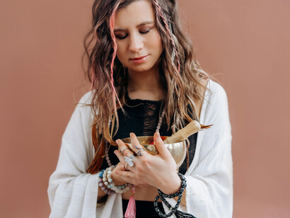 A woman wearing a white gown holding a bronze bowl