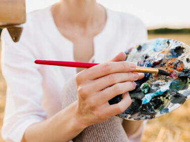 A woman holding a painting palette, glowing with inner light, embarks on a spiritual journey, where abstract spirituality shapes her path, and art becomes her source of salvation