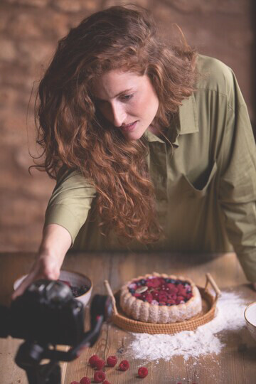 A food influencer capturing herself with a delectable dessert, showcasing current culinary trends through social media food blogging
