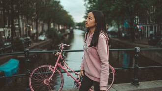 A woman in a hoodie standing on a footbridge in Amsterdam, Netherlands