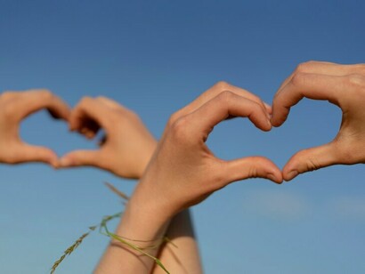 Low-angle view of hands creating a heart shape
