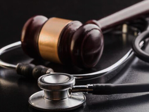 A gavel and stethoscope rest on a wooden table, symbolizing healthcare inequality and the pursuit of social justice in medicine