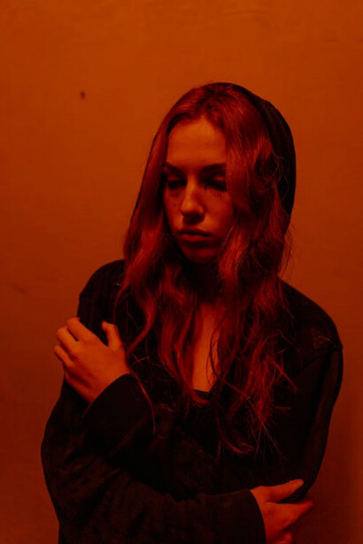 A somber portrayal of a woman enveloped in a hoodie, her posture reflecting the weight of her emotions, as she grapples with the depths of depression