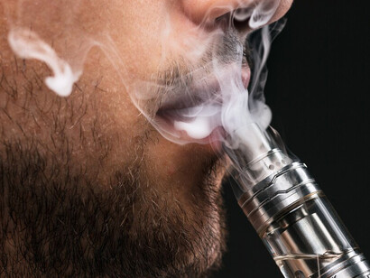 A young man exhaling vapor from an e-cigarette