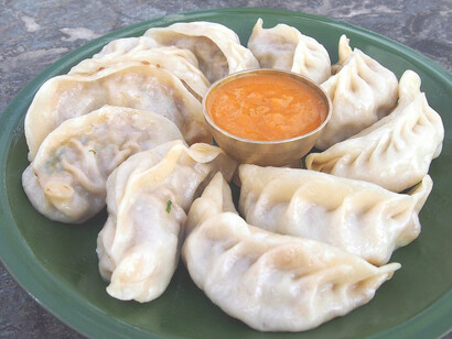 Momos are popular Nepalese dumplings filled with meat or vegetables, either steamed or fried, and often served with a spicy dipping sauce