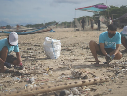 Two Indonesian men actively contribute to beach cleanup efforts on behalf of an ocean conservation group