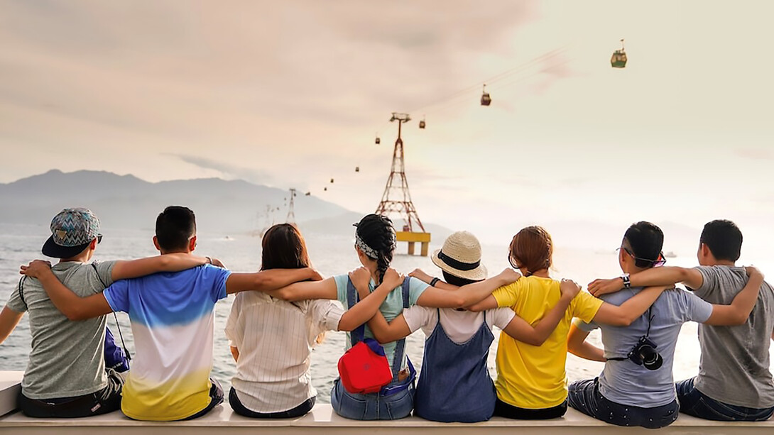 A group of people holding shoulders sitting on wall