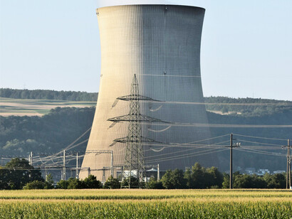 A single concrete cooling tower as the backdrop of a rural power grid
