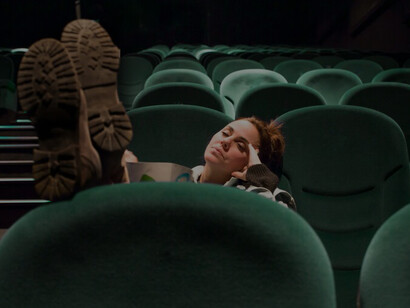A young woman enjoying popcorn in a spacious cinema hall, capturing the essence of the movie experience