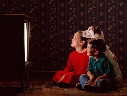 Dos niños viendo la tele con su perro