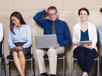 Five job applicants sitting in a waiting room, one of them an elder