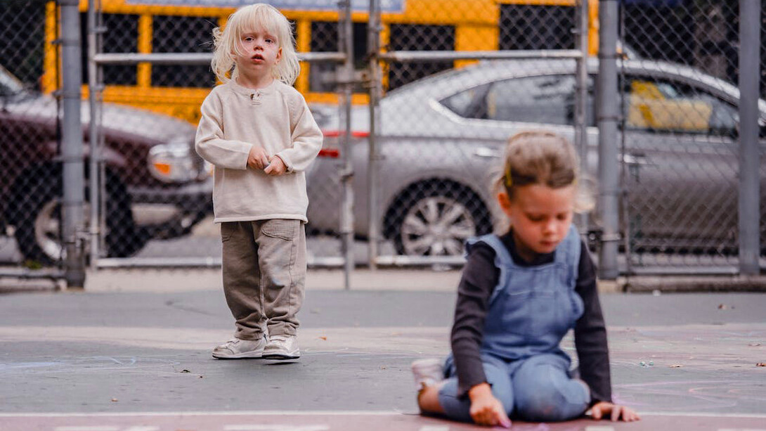Two young friends bring a touch of nostalgia to the playground as they carefully sketch out their hopscotch grid, eager to relive the timeless joy of this classic game