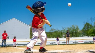 A young boy gripping his bat with determination, reflecting the early spark of competitive spirit