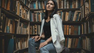 A woman sits in an academic library in Asia, surrounded by shelves filled with books