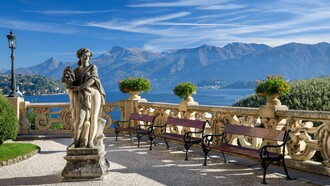 A statue sits on a bench overlooking Lake Como at Villa del Balbianello in Italy