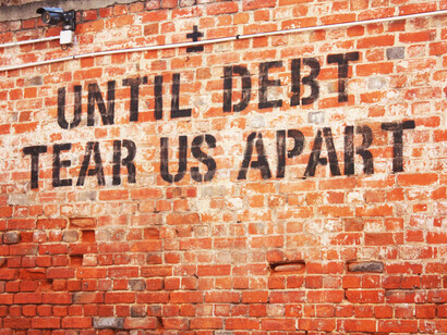 Writing on a wall showing debt as the modern evil