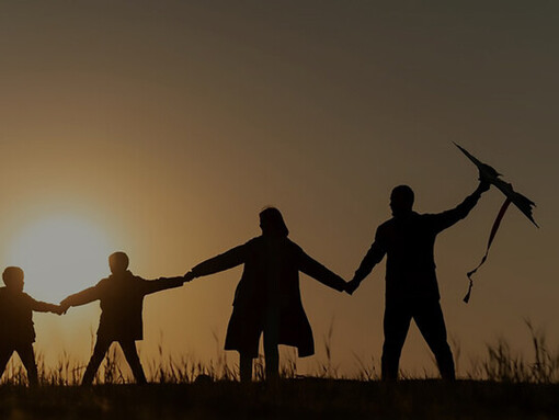A captivating full-shot silhouette captures a joyful family immersed in laughter and play against the vibrant hues of a sunset