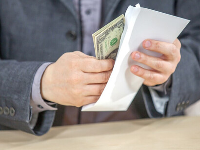 A young businessman sitting in his office, counting cash, driven by corporate greed