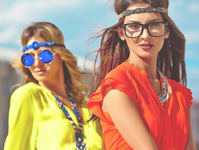 Fashion portrait of two young hippie women models in bright, colorful clothing, enjoying a sunny summer day