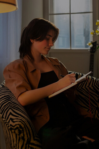 A woman writing in her journal at home explores creative freedom, ethical storytelling, and the publishing industry's role in cultural sensitivity and writing morality