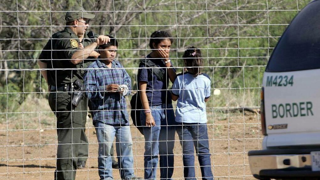 Una patrulla fronteriza detiene a varios niños junto a la alambrada de la frontera estadounidense