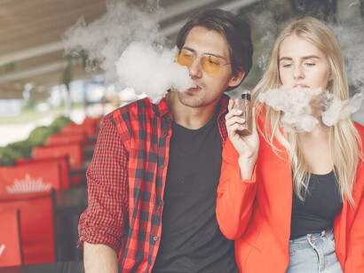 Young couple enjoying their electronic cigarettes, both vaping together