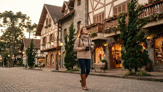 Turista percorre uma rua de Gramado (RS) observando a arquitetura característica da cidade. O artigo mostra que, para pessoas mais introvertidas, viajar pode ser uma experiência ainda mais enriquecedora quando o passeio respeita o próprio ritmo e valoriza a contemplação dos detalhes. Mais do que visitar atrações, o texto convida o leitor a experimentar a viagem com presença, curiosidade e atenção plena. Em vez da pressa para conhecer o maior número possível de lugares, a caminhada tranquila pelas ruas de Gramado simboliza uma forma de viajar que privilegia a observação, o silêncio e a recuperação da energia mental. O artigo explica como essa forma mais consciente de viajar pode beneficiar pessoas com maior sensibilidade aos estímulos do ambiente
