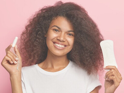African American woman showing concern over menstrual product access, holding a sanitary pad and highlighting issues in personal hygiene