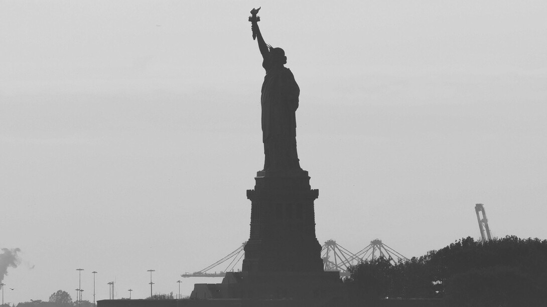 A gray picture of the Statue of Liberty, looming over the island