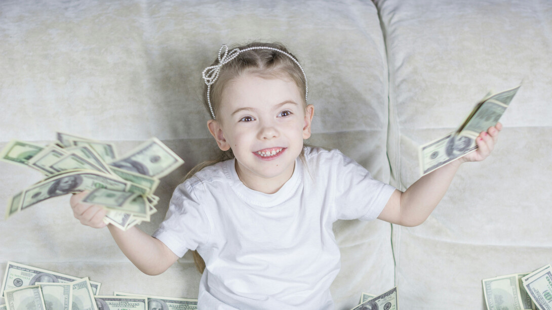 A little girl sitting on a couch holding money