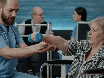 A Danish healthcare worker supports an elderly patient, reflecting the ongoing crisis in Denmark’s health sector and the need for both local and global solutions