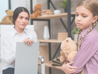 Close-up of a female psychologist providing therapy to a distressed girl holding a teddy bear, exhibiting signs of emotional dysregulation
