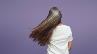 Long brunette hair accented by soft silver strands, reflecting the biological changes that influence hair pigmentation