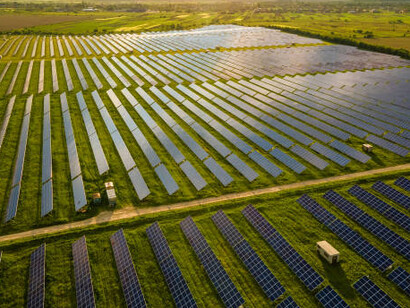Solar photovoltaic panels in striking blue, generating sustainable energy amidst a tranquil rural setting with a beautiful sunset in the background