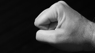 A grayscale image of a clenched fist against a black background