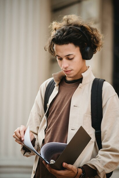 A person wearing headphones looking at their university notes