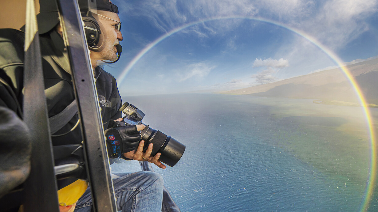 Donn Delson photographing rainbow from a helicopter